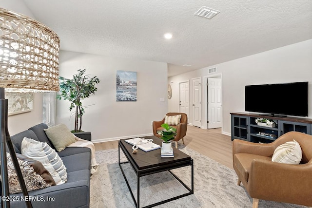 living room featuring a textured ceiling and light hardwood / wood-style flooring