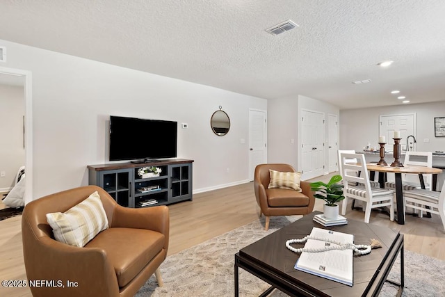 living room with a textured ceiling and light wood-type flooring