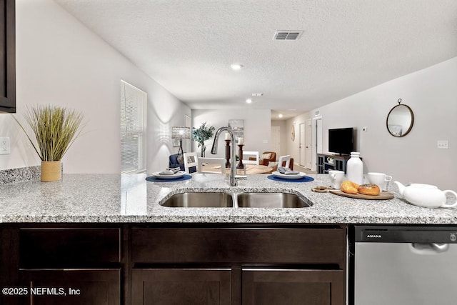 kitchen featuring dishwasher, light stone counters, dark brown cabinetry, and sink