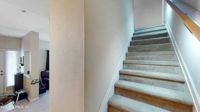 stairs with a healthy amount of sunlight and a textured ceiling