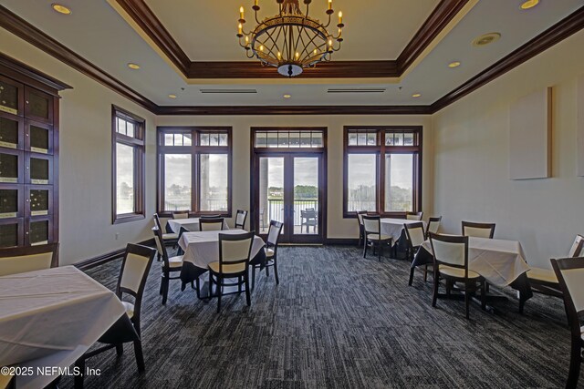 carpeted dining area with a raised ceiling, french doors, ornamental molding, and a chandelier