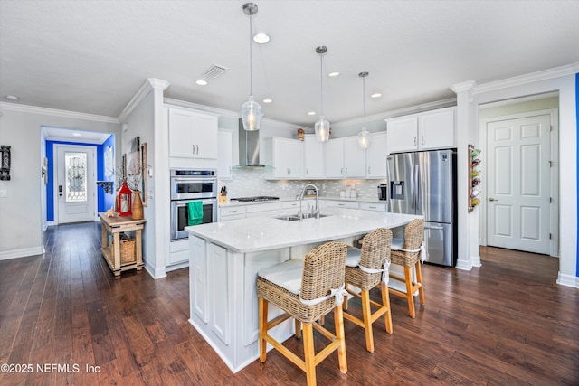 kitchen featuring an island with sink, white cabinets, stainless steel appliances, and decorative light fixtures