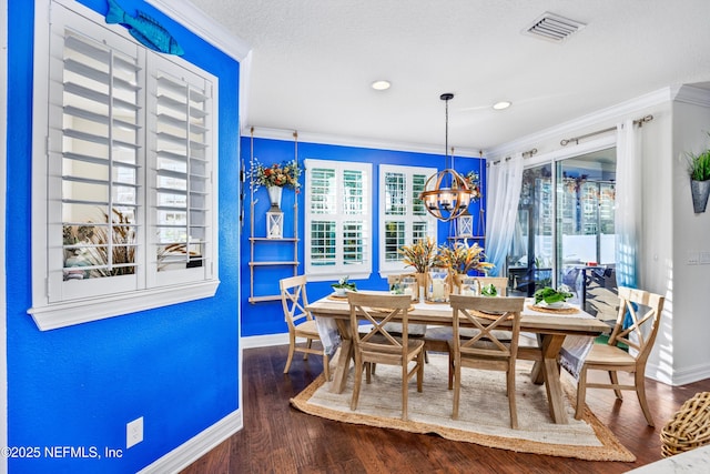 dining area featuring a chandelier, wood-type flooring, a textured ceiling, and ornamental molding