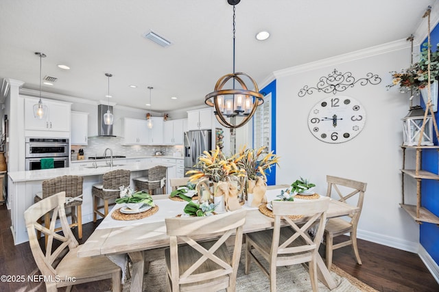 dining area featuring a chandelier, dark hardwood / wood-style floors, ornamental molding, and sink