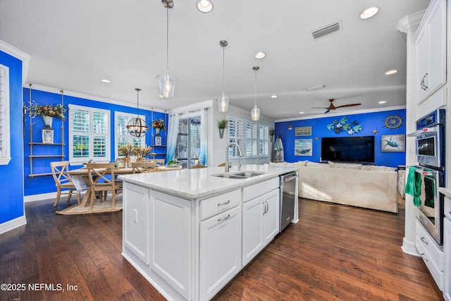 kitchen featuring a center island with sink, white cabinetry, sink, and hanging light fixtures