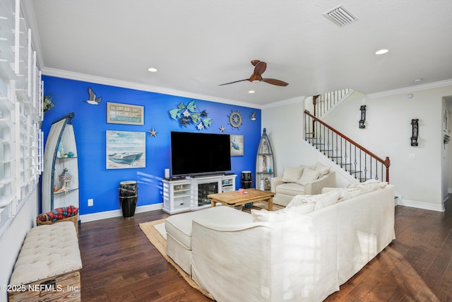 living room with ceiling fan, a fireplace, ornamental molding, and dark wood-type flooring