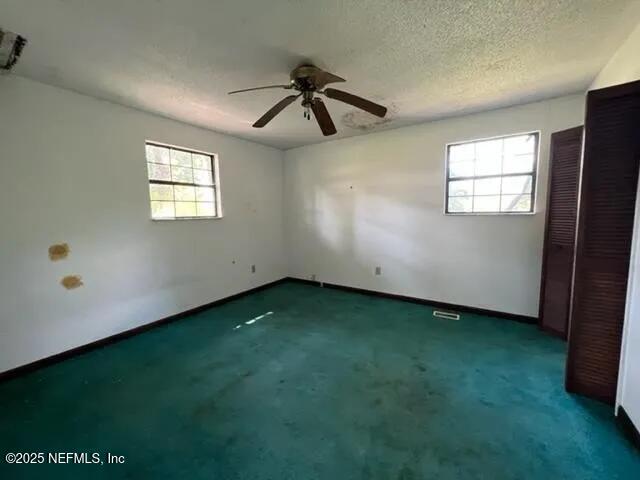 carpeted empty room featuring ceiling fan and a textured ceiling