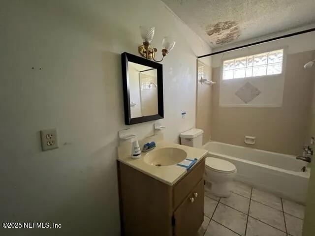 full bathroom with vanity, tile patterned floors, washtub / shower combination, toilet, and a textured ceiling