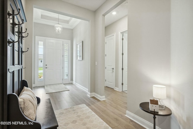 foyer entrance with a tray ceiling, light hardwood / wood-style flooring, and a chandelier