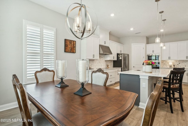 dining room with light wood-type flooring and a notable chandelier