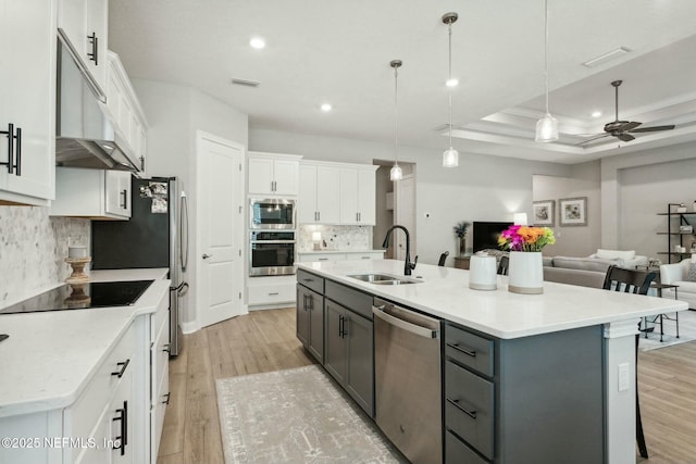 kitchen with stainless steel appliances, white cabinetry, a center island with sink, and sink