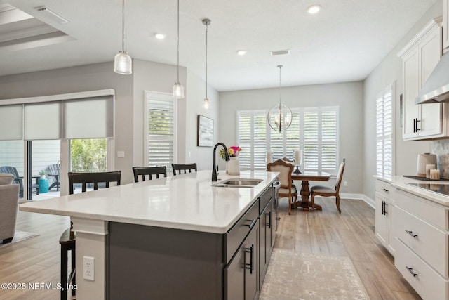 kitchen featuring white cabinetry, sink, a kitchen island with sink, and decorative light fixtures