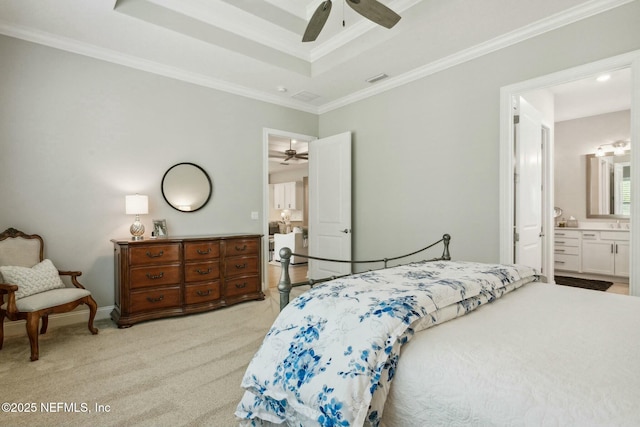 carpeted bedroom with ornamental molding, ensuite bathroom, ceiling fan, and a tray ceiling