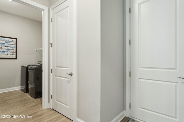 clothes washing area with washer and clothes dryer and light hardwood / wood-style floors