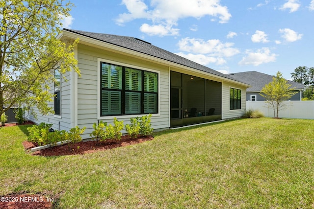 rear view of house featuring a sunroom and a yard