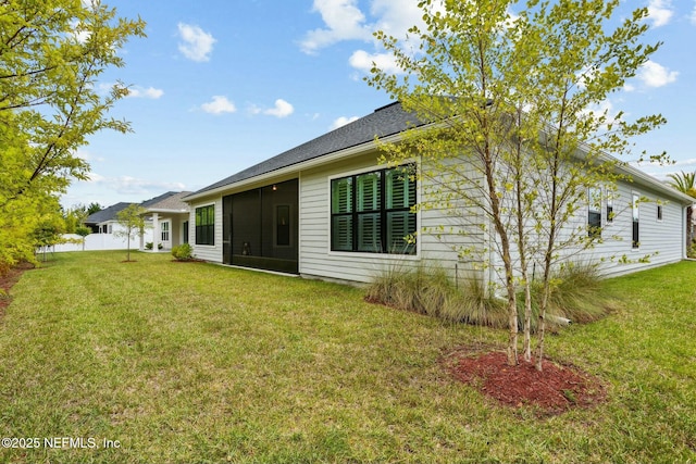 rear view of house featuring a lawn and a sunroom