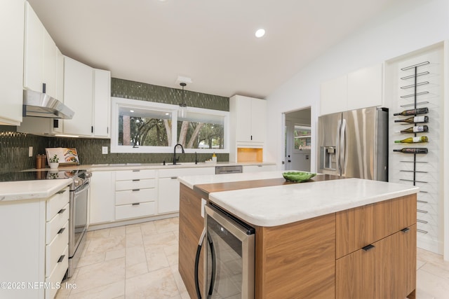 kitchen with a center island, sink, white cabinetry, stainless steel appliances, and beverage cooler