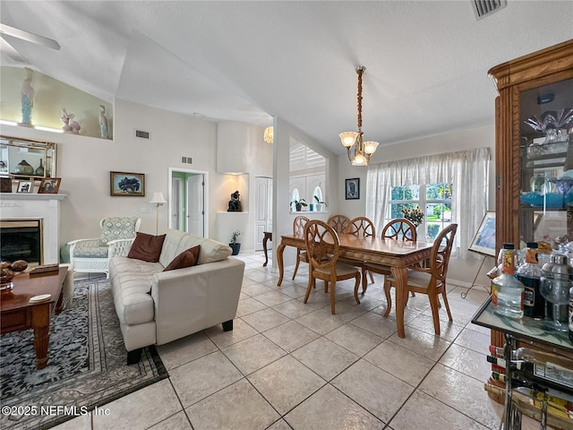 tiled dining space with a textured ceiling, ceiling fan with notable chandelier, and high vaulted ceiling