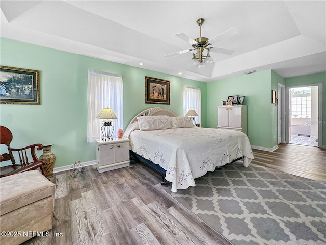 bedroom featuring a raised ceiling, ceiling fan, and hardwood / wood-style floors