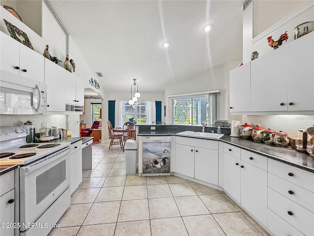 kitchen featuring lofted ceiling, white appliances, white cabinets, sink, and a textured ceiling