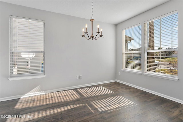 spare room featuring dark wood-type flooring and a chandelier