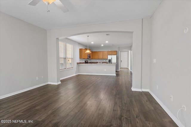 unfurnished living room with dark hardwood / wood-style flooring and ceiling fan