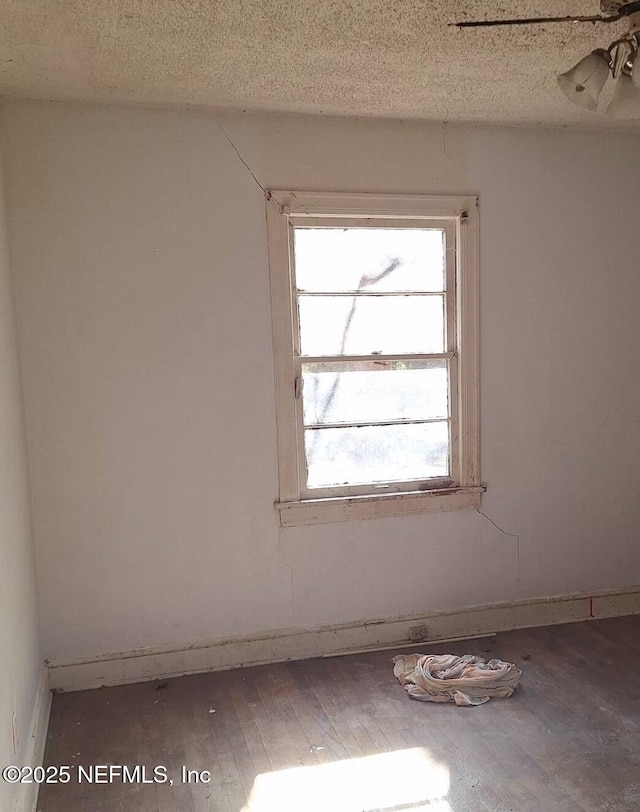 unfurnished room with hardwood / wood-style floors and a textured ceiling