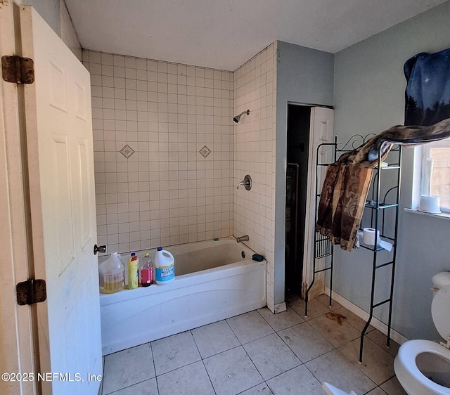 bathroom featuring tiled shower / bath, toilet, and tile patterned flooring