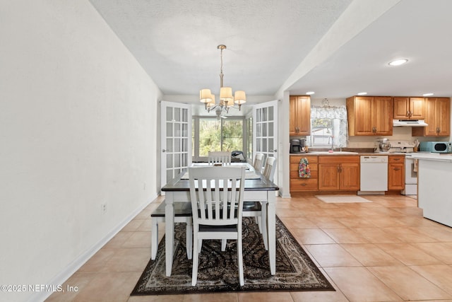 tiled dining area with an inviting chandelier, sink, and a textured ceiling