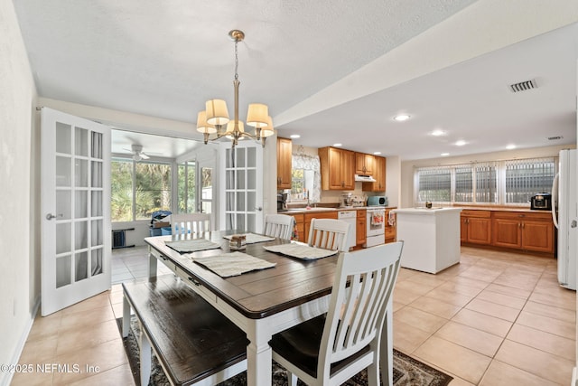 tiled dining space with plenty of natural light, sink, a notable chandelier, and french doors