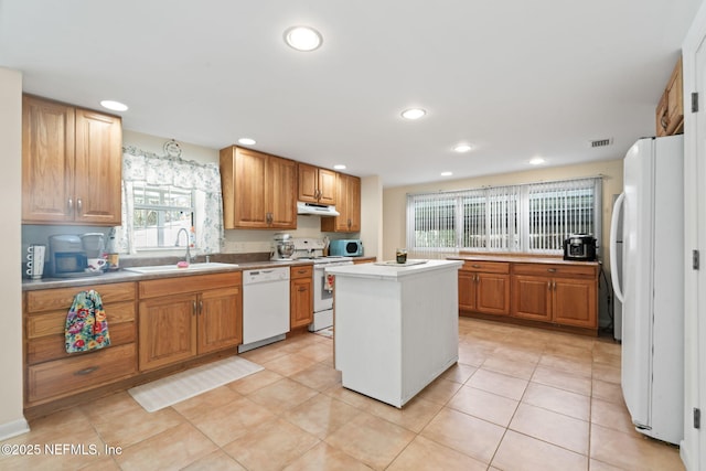 kitchen featuring a center island, sink, light tile patterned floors, and white appliances