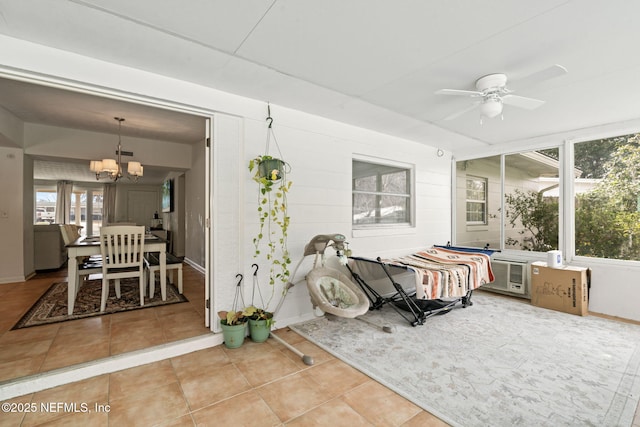 sunroom / solarium featuring ceiling fan with notable chandelier