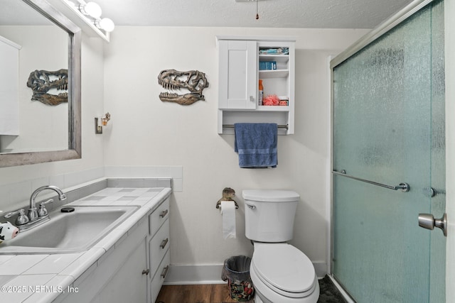 bathroom with vanity, wood-type flooring, a textured ceiling, toilet, and walk in shower