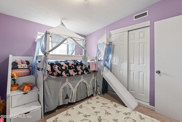 carpeted bedroom with a closet and a textured ceiling