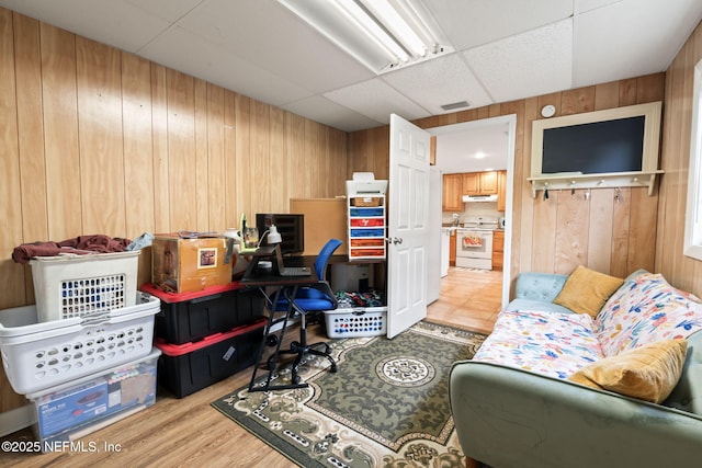 office featuring a paneled ceiling, light hardwood / wood-style floors, and wood walls