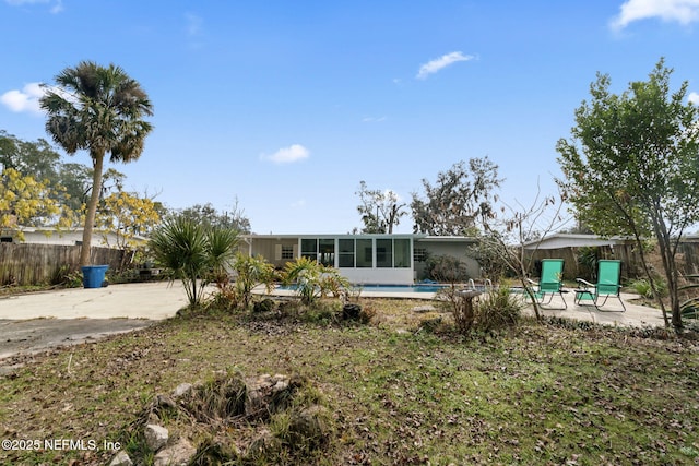 rear view of house featuring a fenced in pool, a sunroom, and a patio