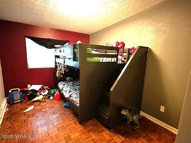 bedroom featuring parquet floors and a textured ceiling