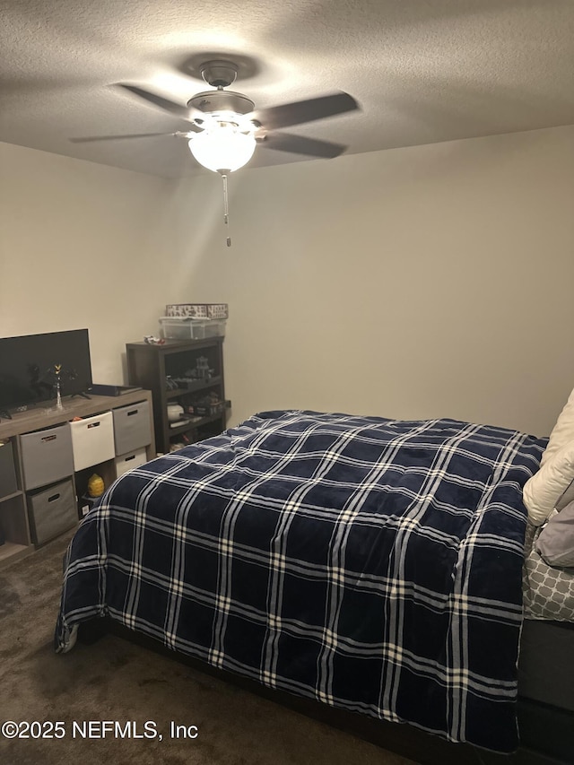 bedroom with ceiling fan, a textured ceiling, and dark colored carpet