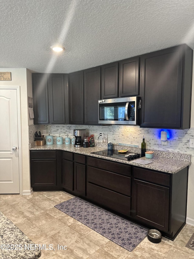 kitchen featuring light stone countertops, a textured ceiling, black electric cooktop, and backsplash