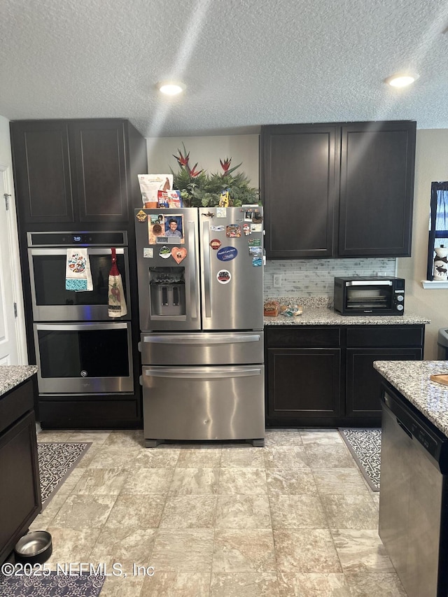 kitchen with light stone counters, a textured ceiling, and appliances with stainless steel finishes