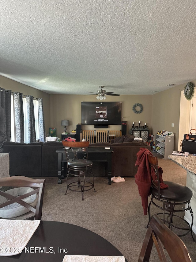 living room with carpet flooring, ceiling fan, and a textured ceiling