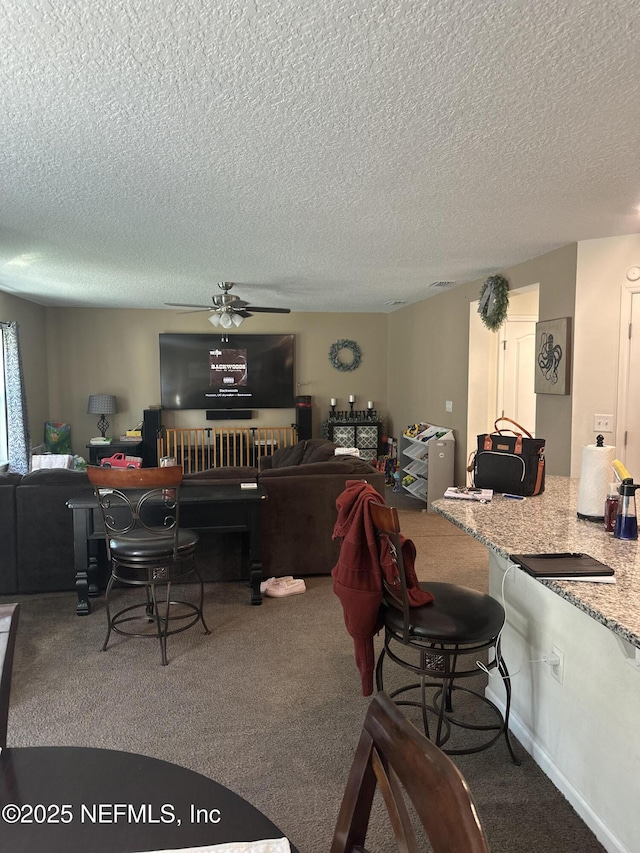 carpeted dining area featuring ceiling fan and a textured ceiling