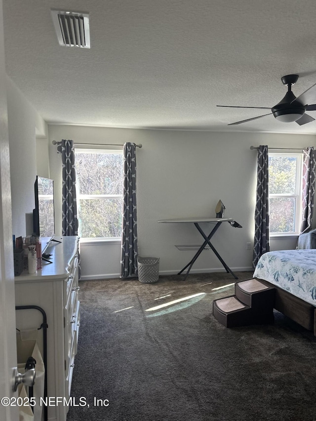 bedroom featuring dark colored carpet, ceiling fan, and a textured ceiling