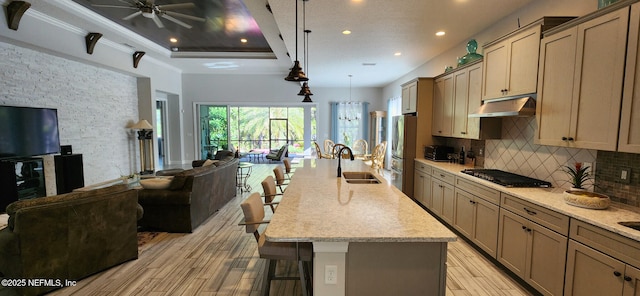 kitchen featuring sink, light stone counters, a spacious island, a kitchen bar, and appliances with stainless steel finishes