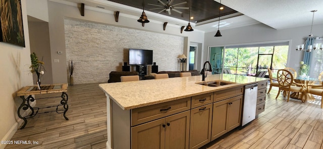 kitchen with pendant lighting, dishwasher, a center island with sink, sink, and light stone countertops