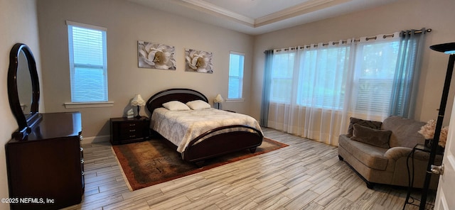 bedroom featuring a raised ceiling, multiple windows, and crown molding