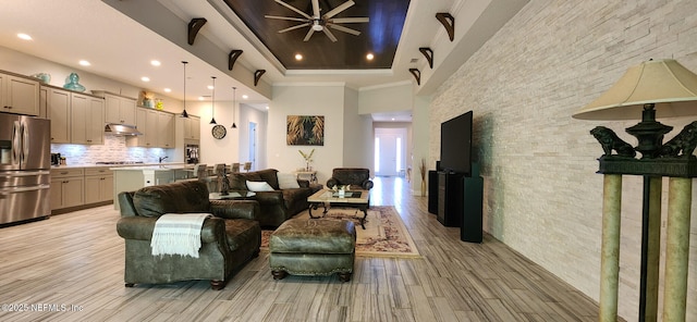 living area with light wood-style flooring, a raised ceiling, ceiling fan, and recessed lighting