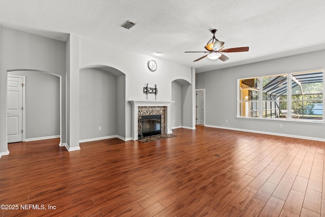 unfurnished living room with ceiling fan, dark hardwood / wood-style floors, and a textured ceiling