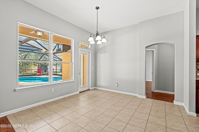 unfurnished room featuring light tile patterned floors, a textured ceiling, and a notable chandelier