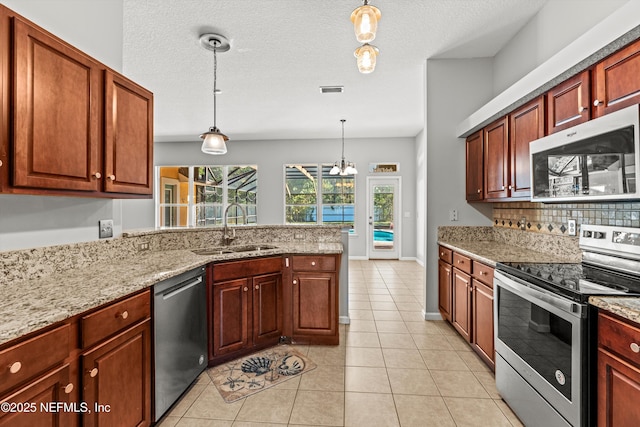 kitchen with a textured ceiling, stainless steel appliances, sink, decorative light fixtures, and light tile patterned flooring